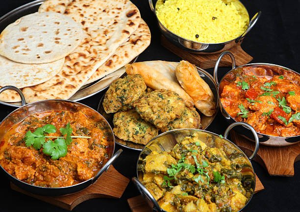 Indian food with curries, rice, naan bread, samosas and pakora.