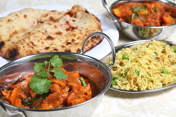 Chicken curry with pillau rice, keema naan, and a vegetable curry