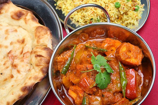 Overhead view of chicken curry with naan bread and pilau rice